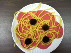 a paper plate with noodles on it and two black holes in the middle that look like eyes