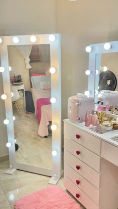 there is a vanity with lights on it and a pink rug in front of the mirror