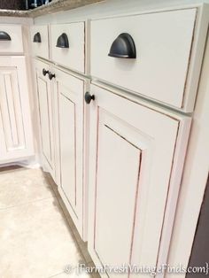 a kitchen with white cabinets and black knobs