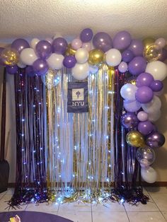 balloons and streamers decorate the backdrop for a new year's eve party in purple, gold and white