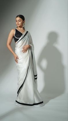 a woman in a white and black sari with her hands on her hips, posing for the camera