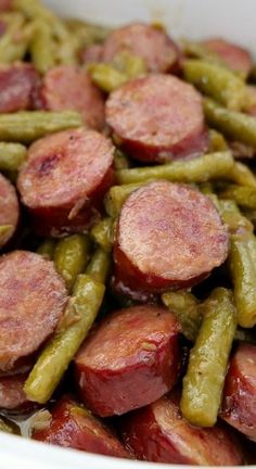 a white bowl filled with green beans and sausage