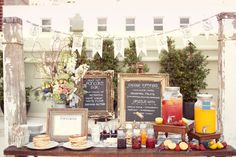 a table topped with lots of food and drinks next to a couple of chalkboards