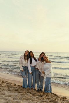 three girls standing on the beach with their arms around each other