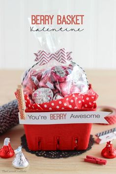 a red basket filled with lots of candy on top of a wooden table next to other candies