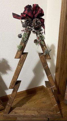 a wooden christmas tree with pine cones and plaid bow