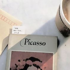 a book sitting on top of a white table next to a cup and saucer