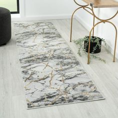 a white and gray area rug with an abstract design on the floor next to a chair