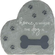 a heart shaped stone with dog paw prints and the words home is where the dog is