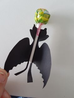 a person holding a lollipop in their hand with the silhouette of a dragon on it