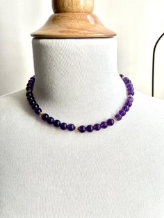 This richly colored amethyst bead necklace features gorgeous 8.25mm round amethyst beads that have been hand strung with delicate white seed pearls and 18k yellow gold beaded spacers. This combination of royal purple, gold, and pearls allow this necklace to look casual or dressy, depending on what you choose to wear it with! Finished with a 14k yellow gold high-polished ball clasp, this is sure to be one of your new favorites!Necklace measures 16.5 inches in length Gold Amethyst Jewelry With 8mm Beads, Elegant Single Strand Amethyst Beaded Necklace, Purple Amethyst Pearl Necklace With Gemstone Beads, Purple Amethyst Gemstone Beads Pearl Necklace, Gold Amethyst Beaded Necklace With Faceted Beads, Purple Amethyst Necklace With 8mm Beads, Gold And Pearls, Drops Necklace, Baroque Jewelry