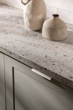 a white vase sitting on top of a counter next to a black and white object