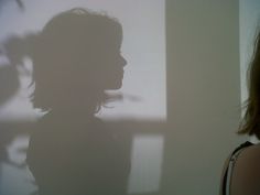 the shadow of a woman's head on a wall