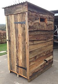 a large wooden outhouse sitting on top of a cement ground next to a bike