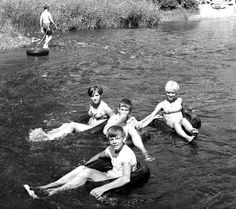 black and white photograph of four boys in the water