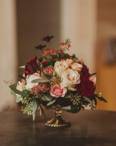 a vase filled with lots of flowers on top of a wooden table next to a phone