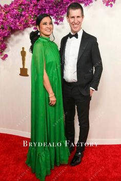 a man and woman in formal wear posing on the red carpet