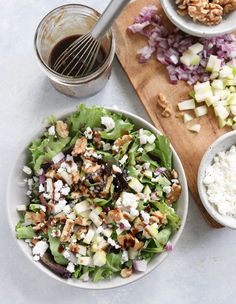 the salad is ready to be eaten on the cutting board with dressing in bowls next to it