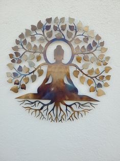 a metal wall hanging with a woman sitting in a yoga pose surrounded by tree branches