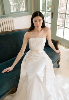 a woman in a white dress sitting on a couch