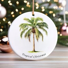 a ceramic christmas ornament with a palm tree on it and the words tropical christmas