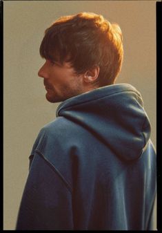 a man in a blue hoodie looking off into the distance with his head tilted back