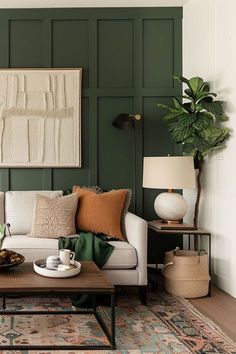 a living room with green paneling and white couches, coffee table, potted plant and lamp