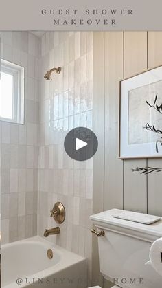 a white toilet sitting next to a bath tub in a bathroom under a framed painting