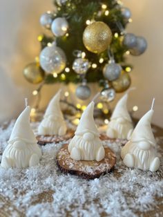 some white frosted cookies sitting on top of a table next to a christmas tree