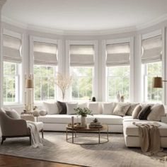 a living room filled with lots of furniture and windows covered in white shades on top of them