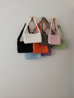 six crocheted purses hanging on a wall