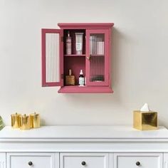 a pink cabinet sitting on top of a white dresser