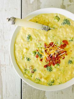 a white bowl filled with cheese and broccoli soup on top of a wooden table