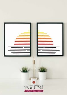 two framed pictures on the wall with plants in front of them and an image of a rainbow