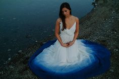 a pregnant woman sitting on an inflatable mattress by the water's edge