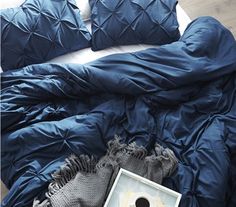 a blue comforter and pillows on a bed with a white box in the middle