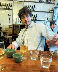 a man sitting at a table filled with glasses of wine and drinks in front of him