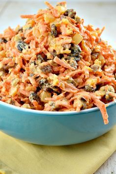 a blue bowl filled with carrot salad on top of a yellow napkin