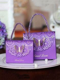 two purple bags sitting on top of a plate next to each other with butterfly decorations