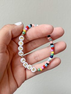 a hand holding a beaded bracelet with the word love spelled in small letters on it