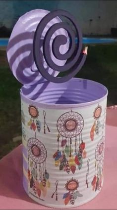 a tin can with a decorative design on it and a paper fan sticking out of the top