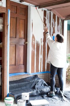 a woman is painting the interior of a house with white paint and brown wood doors