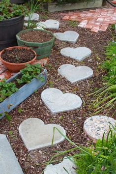 several heart shaped stepping stones on the ground in front of potted plants and flowers