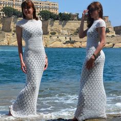 two beautiful women standing in the ocean next to each other wearing long dresses and sunglasses