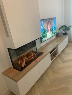 a flat screen tv sitting on top of a wooden shelf next to a fire place