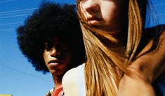 two women standing next to each other in front of a blue sky and power lines