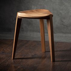 a wooden stool sitting on top of a hard wood floor next to a gray wall