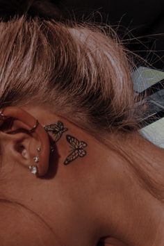 a woman with a butterfly tattoo on her left side behind the ear is laying down