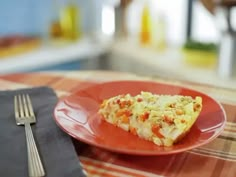 a red plate topped with a slice of pizza on top of a checkered table cloth