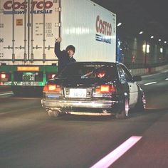 a man waving from the hood of a car in front of a semi - truck